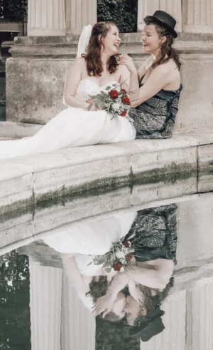Lesbisches Brautpaar am Springbrunnen küssend mit Spiegelung im Wasser Lesbisches Brautpaar